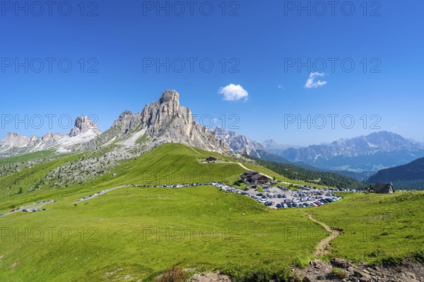 Panoramic view of the parking area at passo giau in the dolomites on a sunny summer day, highlighting majestic peaks and lush landscapes