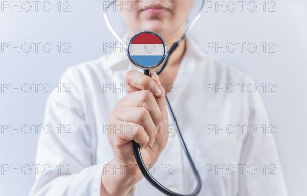 Female doctor holding stethoscope with Luxembourg flag. National health system of Luxembourg