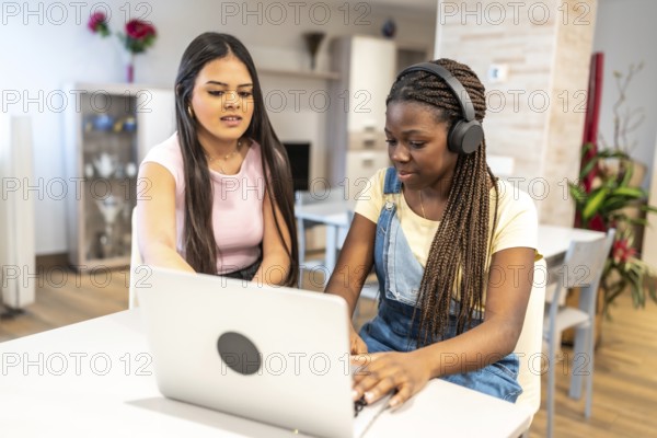 Two teenage girls collaborating on a school project, working together on a laptop at home, sharing ideas and supporting each other