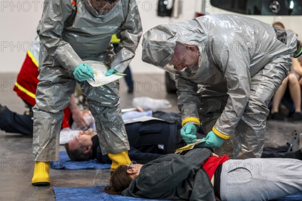 Viewing of patients in front of decontamination of injured persons after an assumed accident with hazardous substances, patient is intubated and ventilated by hand, fire brigade and aid organisations practise setting up and operating a decontamination station, injured persons are viewed and then washed in a special shower tent to remove possible hazardous substances and chemicals in order to avoid further injuries, the emergency services wear special, ventilated protective suits, large-scale exercise by the Essen fire brigade