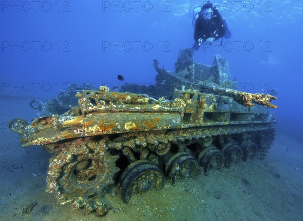 Underwater photo of diver swimming above looking at as an attraction for underwater sportsmen sunken US American tank M42 Duster with anti-aircraft gun at dive site Seven Sisters, Red Sea, Gulf of Aqaba, Aqaba, Aqaba, Jordan, Asia