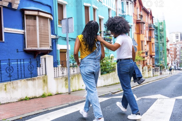 Rear view of two african american young friends walking along a colorful street