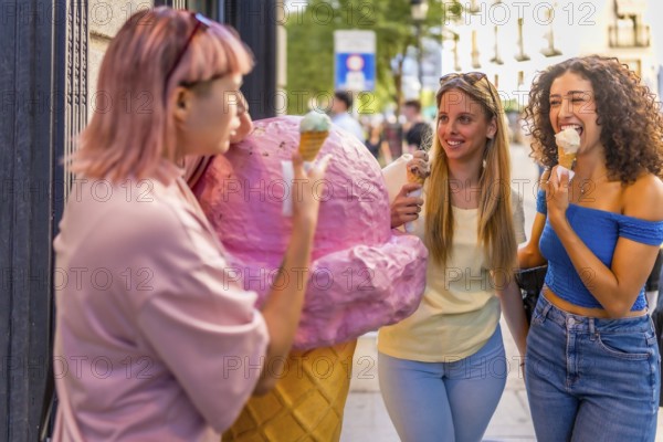 Girls having fun eating ice cream in the city standing in front of ice cream store with a giant figure of a cone