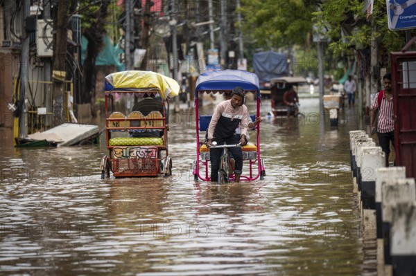 Commuters in cycle rickshaws as they wade through a flooded street after heavy rains in Guwahati, India on April 28, 2025