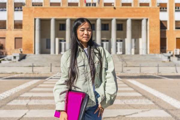 Portrait of a confident chines university student standing in the street at the entrance of the building
