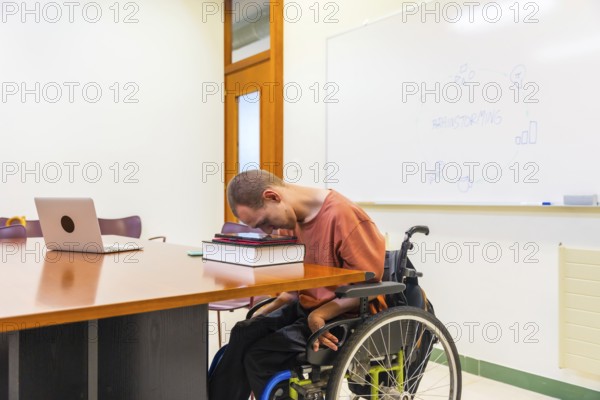 Side view horizontal photo with copy space of a man with cerebral palsy using digital tablet working in coworking