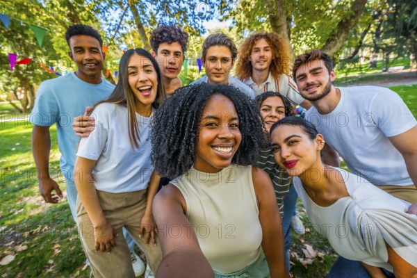 Happy african woman taking selfie with multi-ethnic friends in park during a celebration