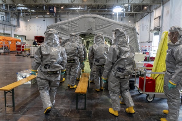 Decontamination of injured persons after an assumed accident involving hazardous substances, fire brigade and aid organisations practise setting up and operating a decontamination station, injured persons are sighted and then washed in a special shower tent to remove possible hazardous substances and chemicals in order to avoid further injuries, the emergency services wear special, ventilated protective suits, large-scale exercise by the Essen fire brigade