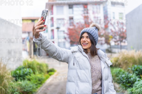 Beauty woman in winter clothes taking selfie with mobile phone in the city