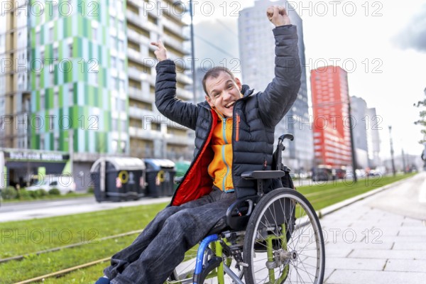 Happy disabled man celebrating in a wheelchair near modern buildings, enjoying his freedom and mobility in the urban environment