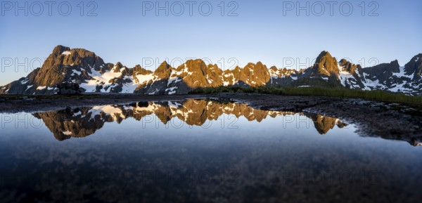 Rocky mountain peaks reflected in a small pond, mountain landscape with alpenglow at sunrise, at the Trollfjord Hytta, at the Trollfjord, Lofoten and Vesterålen, Nordland, Norway, Europe