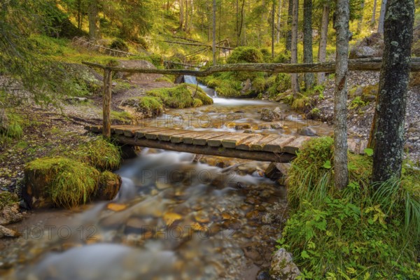 View of a rustic wooden bridge leading over a torrent, long exposure, Dolomites, Puez-Geisler nature park Park, St. Magdalena, Funes, Villnöss Valley, South Tyrol, Italy, Europe