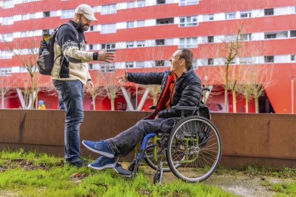 Two male friends meeting in the city, one of them using a wheelchair, greeting each other happily