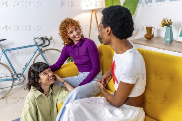 Transgender man and lesbian friends talking sitting on the sofa relaxed at home