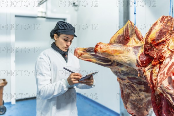 Female butcher making quality report in slaughterhouse writing in clipboard