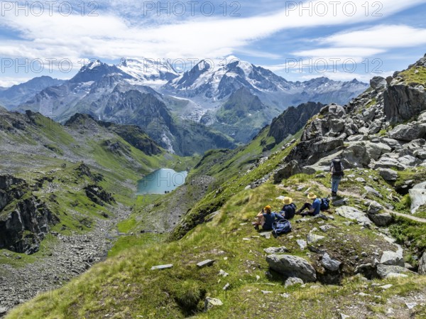 Hikers taking a break, mountain lake Lac de Louvie with glaciated summit of the Grand Combin, Val de Bagnes, Valais, Switzerland, Europe
