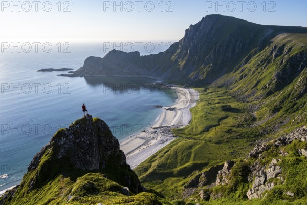 Climber on a rock, view of picturesque coastal landscape, steep coast with peak Måtind or Måtinden, Høyvika beach and sea, hike to the summit of Måtind, Andøya island, Vesterålen, Nordland, Norway, Europe