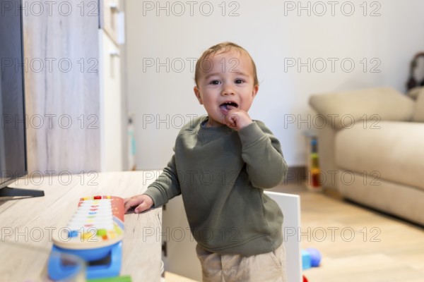 Curious toddler engaging with colorful musical toy, exploring sounds and developing musicality in a playful home environment