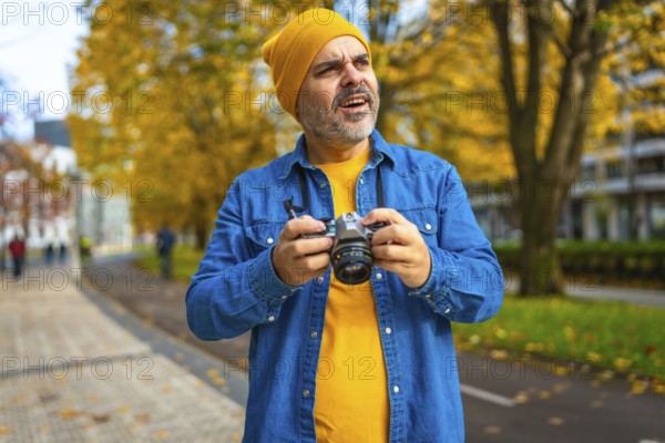 Mature man in urban clothes photographing a city while visiting in autumn