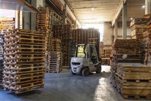 Full length photo with no people of a forklift in a pallet storage room in a recycling plant