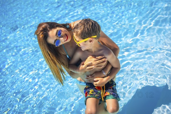 Caucasian beauty mother and boy in a blue swimming pool together