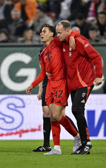 Jamal Musiala FC Bayern Munich FCB (42) injured Injury is escorted off the pitch by the attendants WWK Arena, Augsburg, Bavaria, Germany, Europe