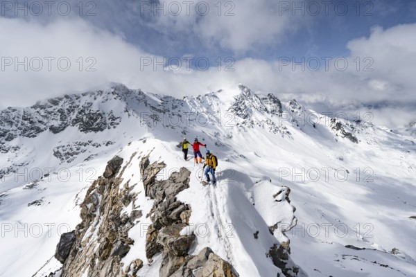 Three mountaineers climbing the narrow ridge of Piz Laviner, view of mountain panorama in winter mountain landscape, Grisons Haute Route, Albula Alps, Rhaetian Alps, Grisons, Eastern Switzerland, Switzerland, Europe