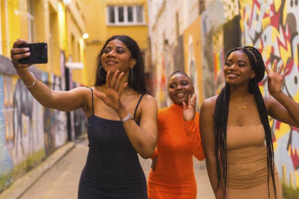 San Sebastián, Gipuzkoa Spain, February 2021: Three girls taking a selfie. Fashionable urban style with three black African girls on a city street, tight dresses