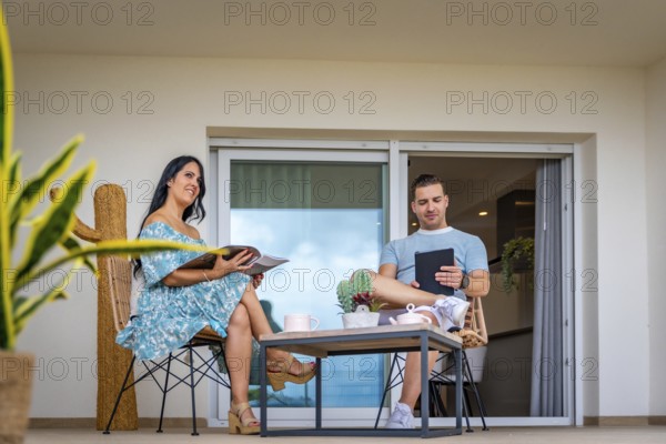 Daydreaming of a couple reading and using tablet drinking coffee in the patio