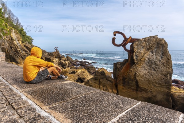 A young man in a yellow sweatshirt visiting the Peine del Viento in San Sebastián. Province of Gipuzkoa, Basque Country. Spain