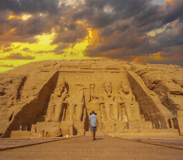 A young man walking towards the Abu Simbel Temple in southern Egypt in Nubia next to Lake Nasser. Temple of Pharaoh Ramses II, travel lifestyle