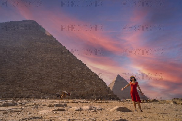 A young girl in a red dress at the pyramid of Cheops the largest pyramid at sunset. The pyramids of Giza the oldest funerary monument in the world. In the city of Cairo, Egypt, Africa