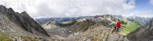 Panorama, mountaineer sitting on a rock, on a steep rocky ridge, on the summit of the Lasörling, view of the mountain panorama of the Venediger group, Lasörling group, Hohe Tauern National Park, East Tyrol, Tyrol, Austria, Europe