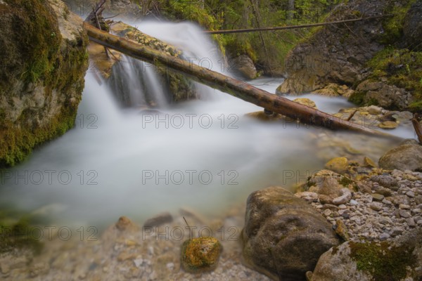 A tree trunk lies across a waterfall, long exposure, Dolomites, Puez-Geisler nature park Park, St. Magdalena, Villnöß, Funes, Villnößtal, South Tyrol, Italy, Europe