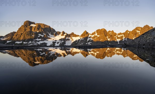 Rocky mountain peaks reflected in a small pond, mountain landscape with alpenglow at sunrise, at the Trollfjord Hytta, at the Trollfjord, Lofoten and Vesterålen, Nordland, Norway, Europe