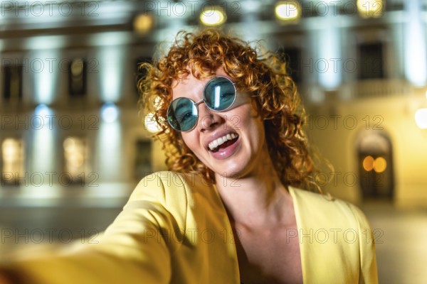 Woman enjoying the city night and taking a selfie standing alone and smiling
