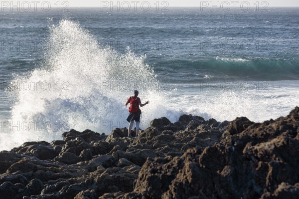 Rocky west coast, black lava coast, coastline, hiker looking at the surf, El Golfo, Yaiza, Lanzarote, Spain, Europe