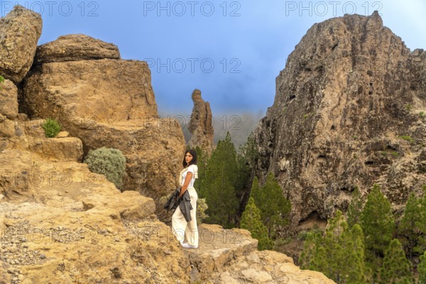 Woman standing on a rocky viewpoint enjoying the scenic landscape of roque nublo, a volcanic rock formation in gran canaria, spain