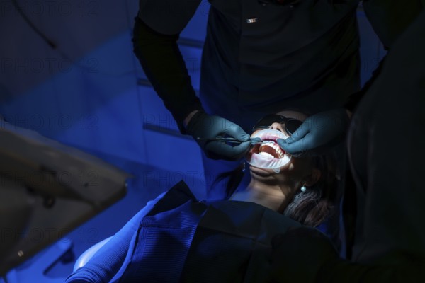 Dentist applying whitening gel on patient's teeth, enhancing oral health and creating a radiant, confident smile in a modern dental clinic