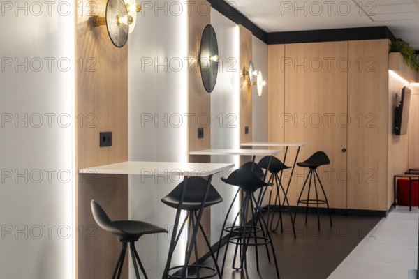 Modern airport workspace offering travelers a stylish area to work or relax, featuring sleek tables, comfortable bar stools, and power outlets