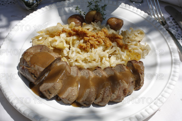 Swabian cuisine, roast venison with spaetzle, chestnuts and breadcrumbs, breadcrumbs, saddle of venison arranged on a plate, gravy, game dish, meat, main course, gravy, cutlery, knife, fork, grandmother's kitchen, regional, home cooking, typical Swabian, traditional cuisine, festive tablecloth, food photography, studio, Germany, Europe