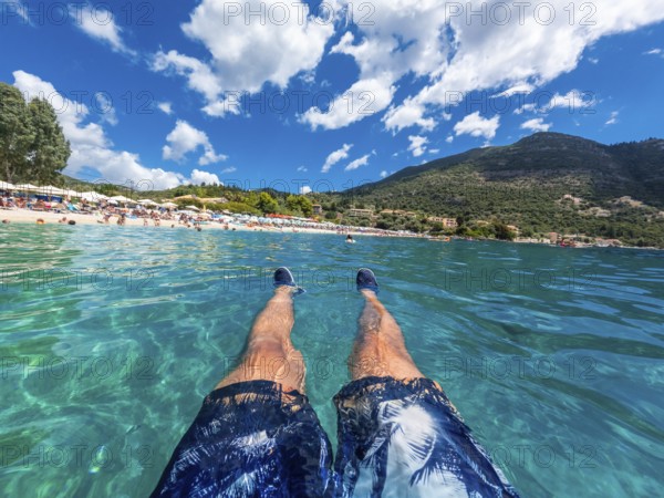A man resting in the sea on the beach in summer of Paralia Mikros Gialos in the south of the island of Lefkada. Greece