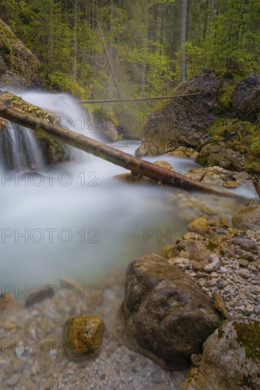 A tree trunk lies across a waterfall, long exposure, Dolomites, Puez-Geisler nature park Park, St. Magdalena, Villnöß, Funes, Villnößtal, South Tyrol, Italy, Europe
