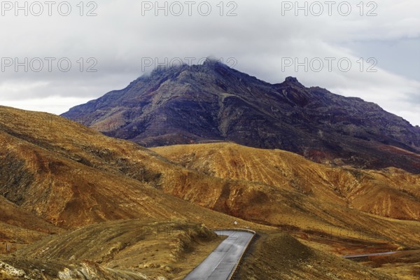 A winding road leads through a mountainous landscape under a cloudy sky, Pajara, Fuerteventura, Canary Islands, Spain, Europe