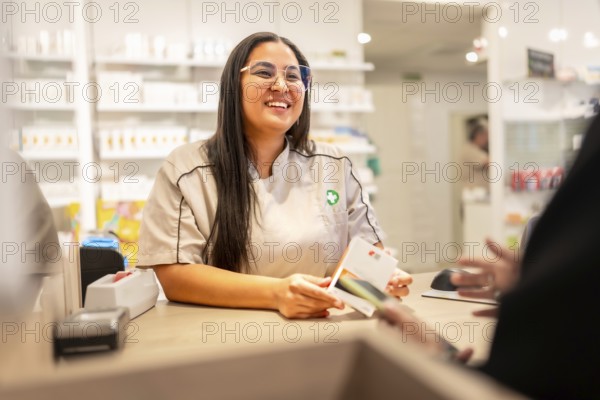 Cheerful pharmacist attending a client in the counter of a modern store