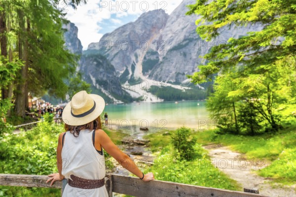 Tourist enjoying breathtaking view of lake braies, surrounded by majestic mountains and lush greenery in the dolomites, italy