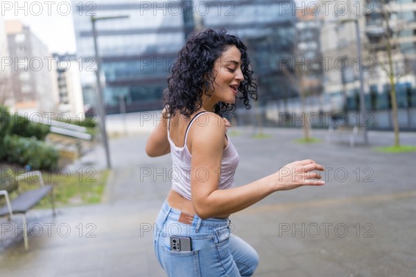Carefree young woman dancing in the city with smartphone in her pocket, enjoying music and urban lifestyle