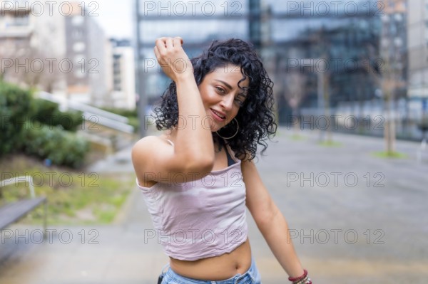 Carefree young woman enjoying music through headphones, dancing in a city park, expressing joy and freedom