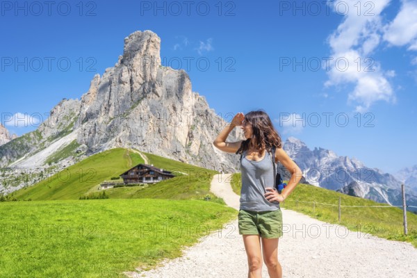 Female hiker walking along a mountain path, soaking in the breathtaking views of the dolomites during a sunny summer day