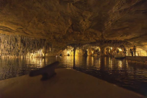 Tourists enjoying a boat trip on the martel lake inside the drach caves, illuminated by colorful lights, creating a magical and mysterious atmosphere